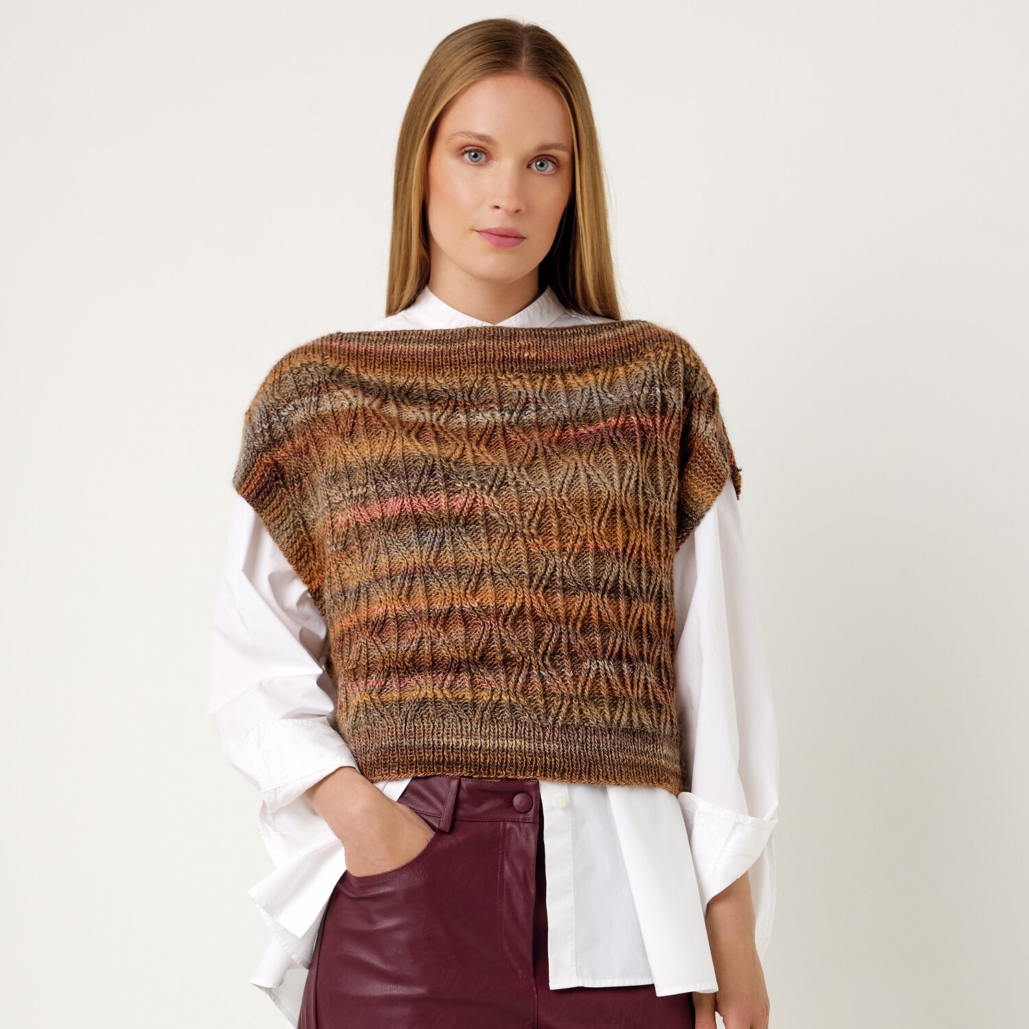 Strickset Top Modell 17 aus Die Neue Masche No. 13 von idee. Creativmarkt Strickset Top Modell 17 aus Die Neue Masche No. 13: Frau trägt gestricktes Oberteil in Brauntönen über weißer Bluse.