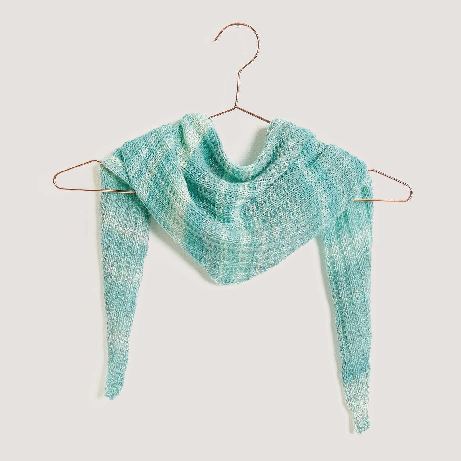 Strickset Dreieckstuch Modell 12 aus Tücher Special in Aqua, präsentiert auf einem Kleiderbügel. Ideal für modische Handarbeitsprojekte.