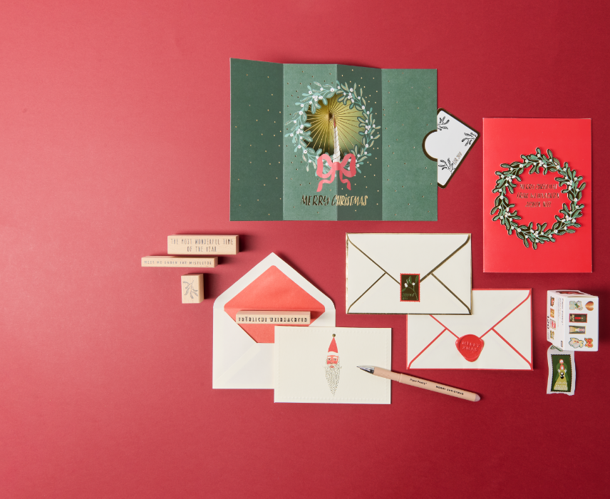 Selbstgestaltete Weihnachtskarten mit Stempeln und Briefpapier auf rotem Hintergrund.