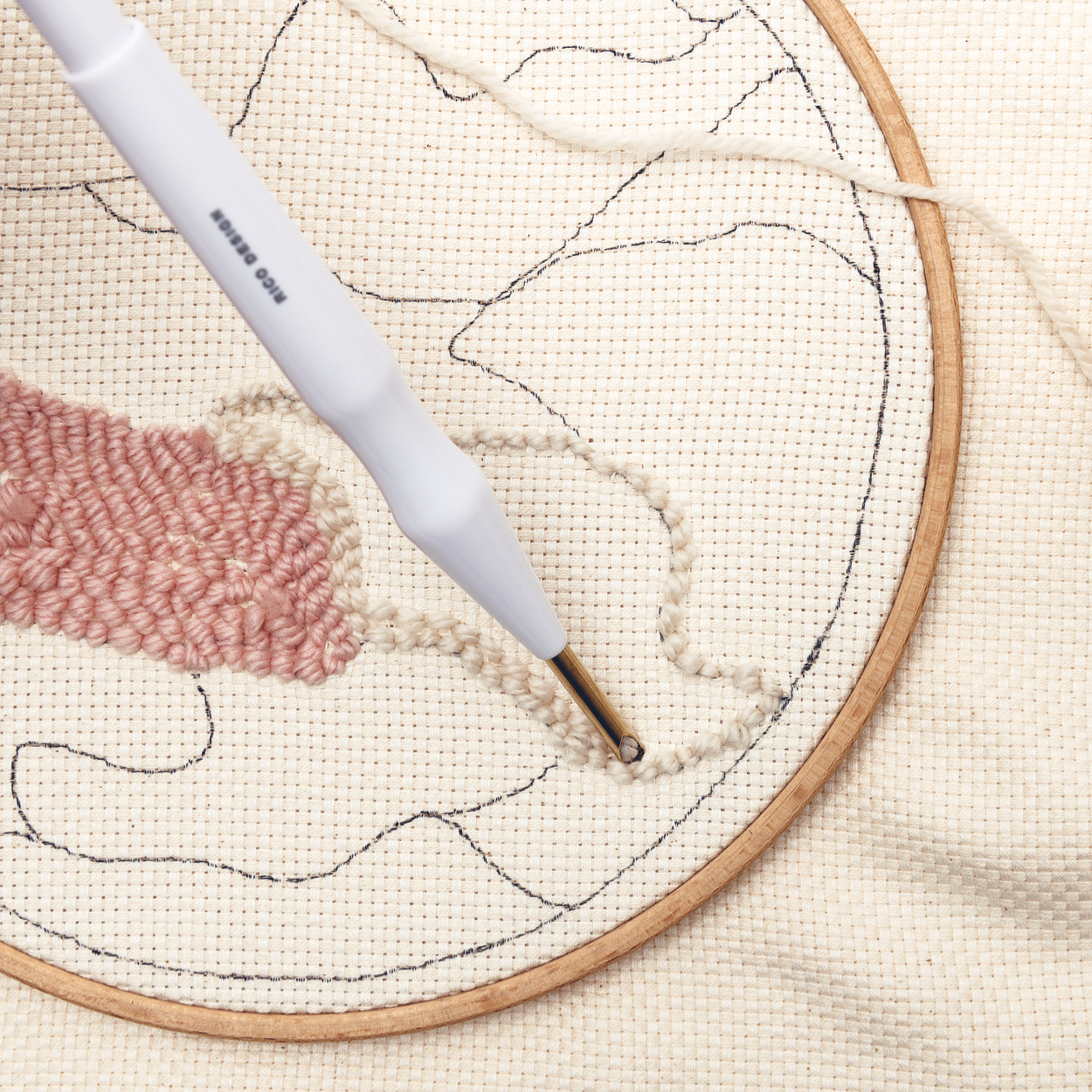Punch Needle sticht Wolle in eingespannten Stoff im Stickrahmen