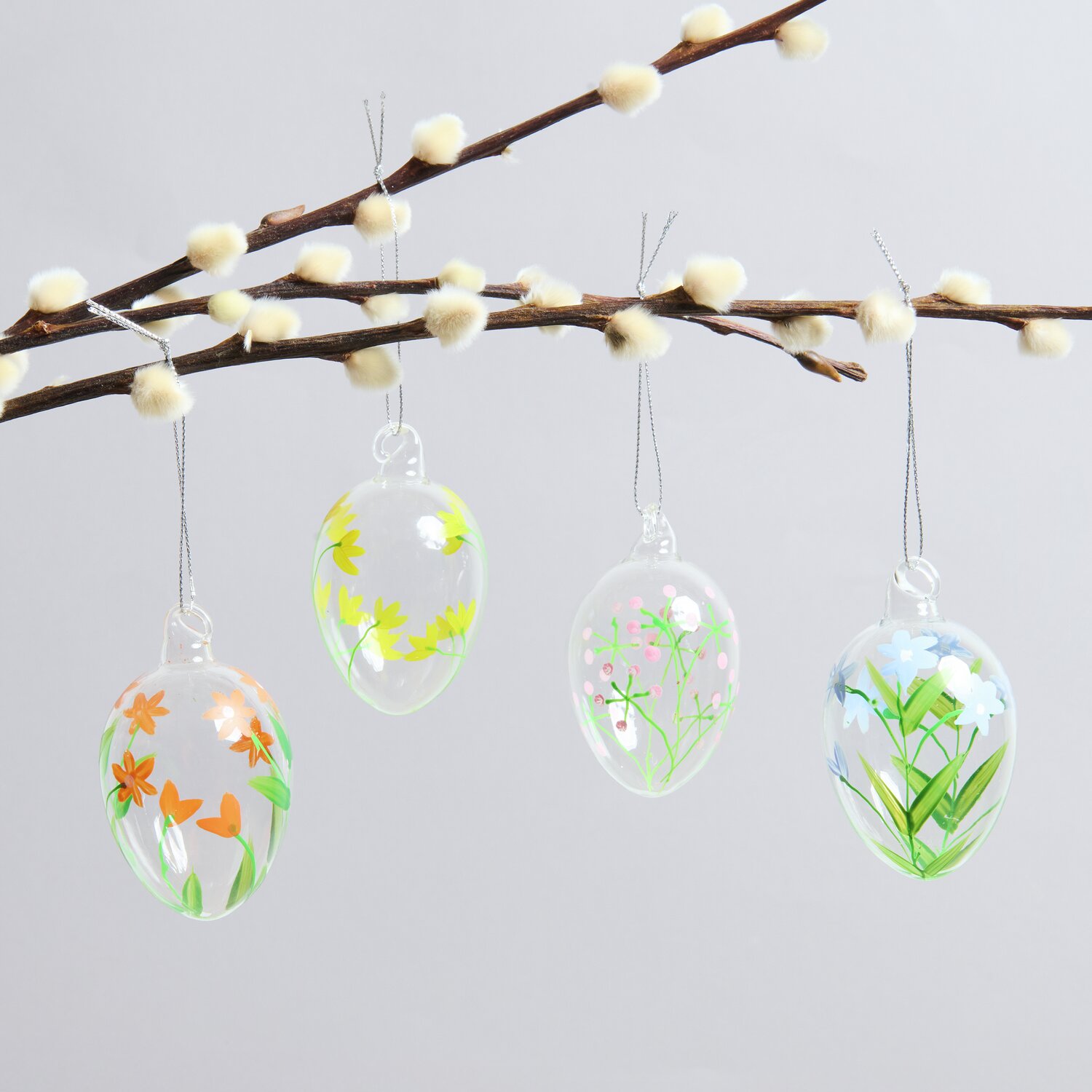 Glas Eier Frühlingswiese handbemalt 4 Stück, dekorative Ostereier mit floralen Mustern, hängend an einem Ast, ideal für Frühlingsdekorationen.