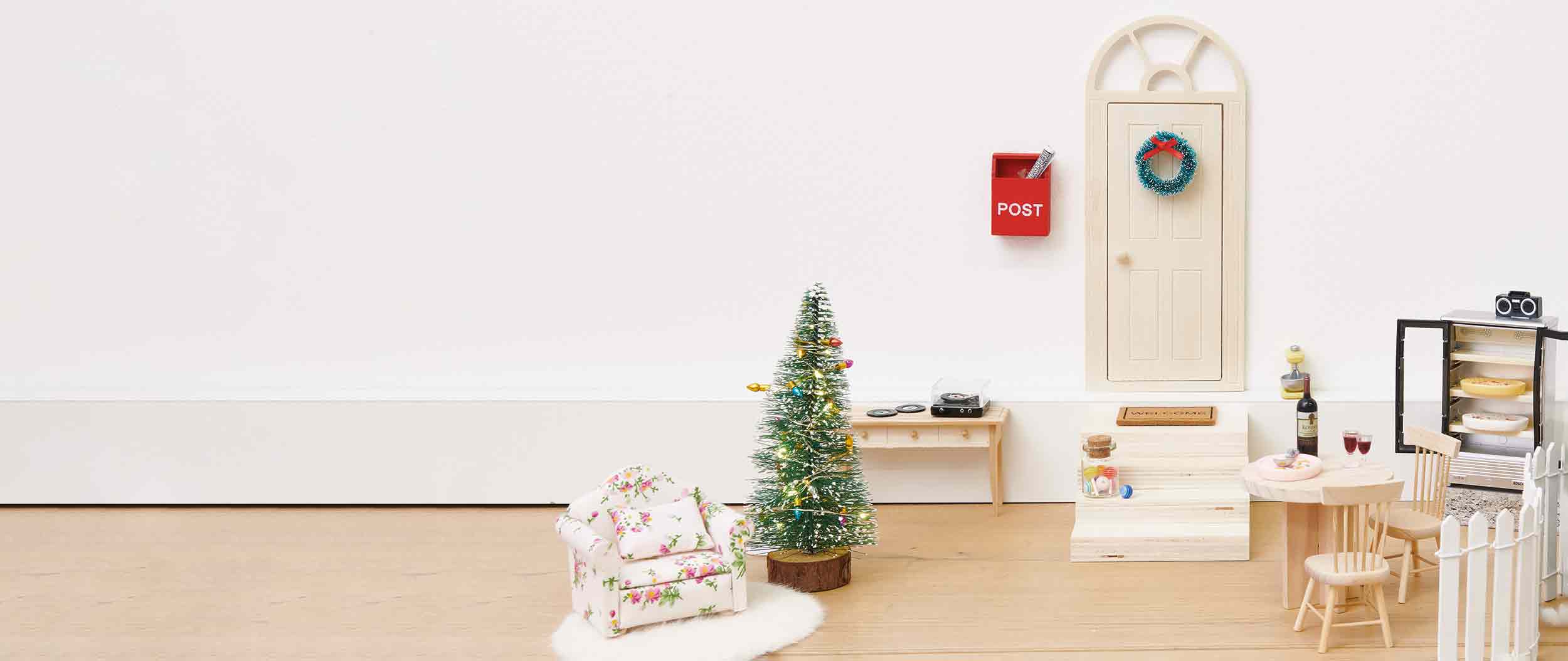 Eine Wichtelwelt bestehend aus einer Tür, Treppe, Weihnachtsbaum, Tisch und Sessel. Fotosetting Fußleiste.