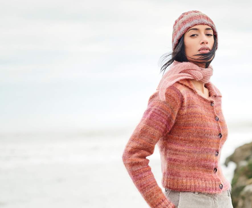 Frau trägt Strickjacke, -schal, -mütze