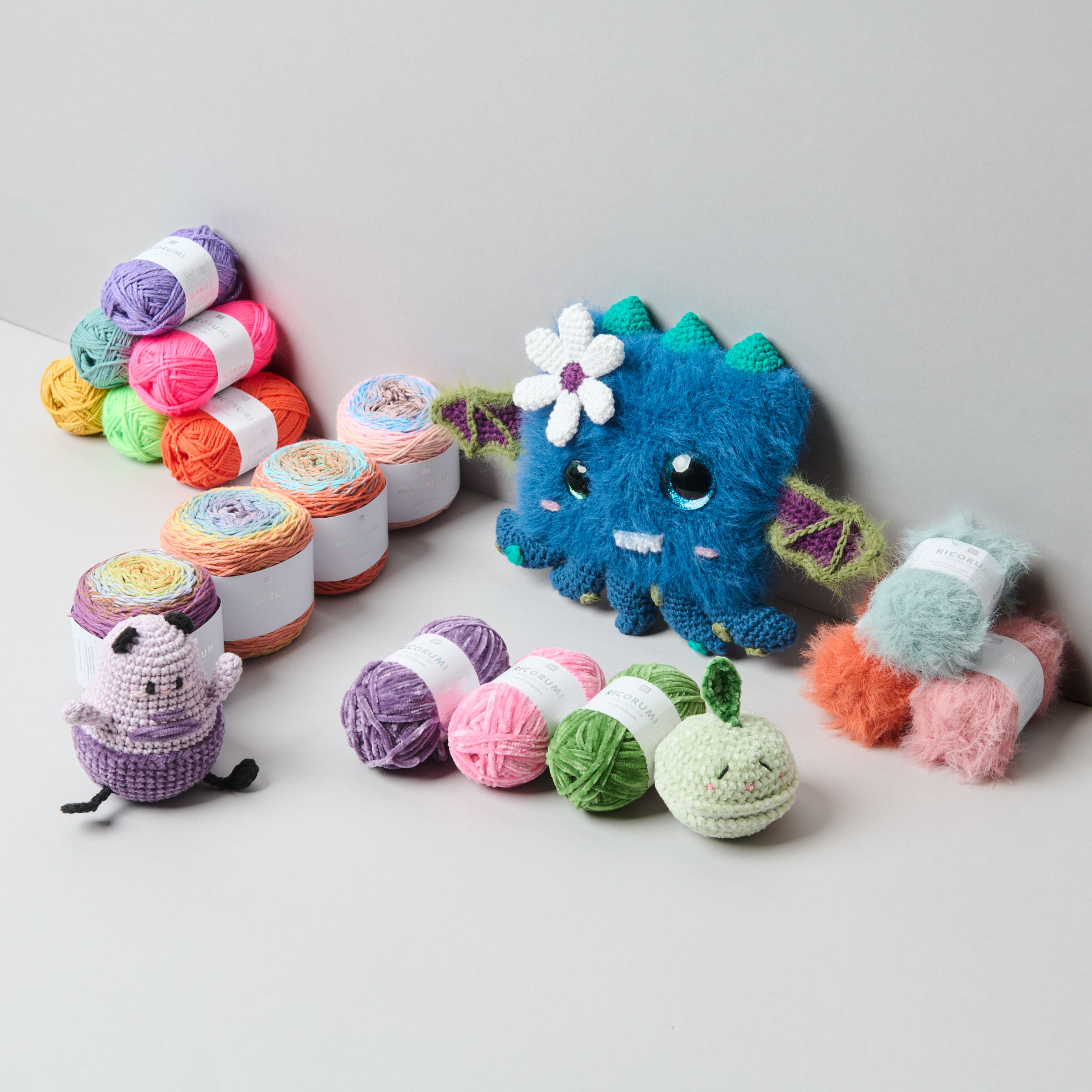 Viele Häkelgarne und gehäkelte Amigurumi Monster. Fotosetting graue Ecke.