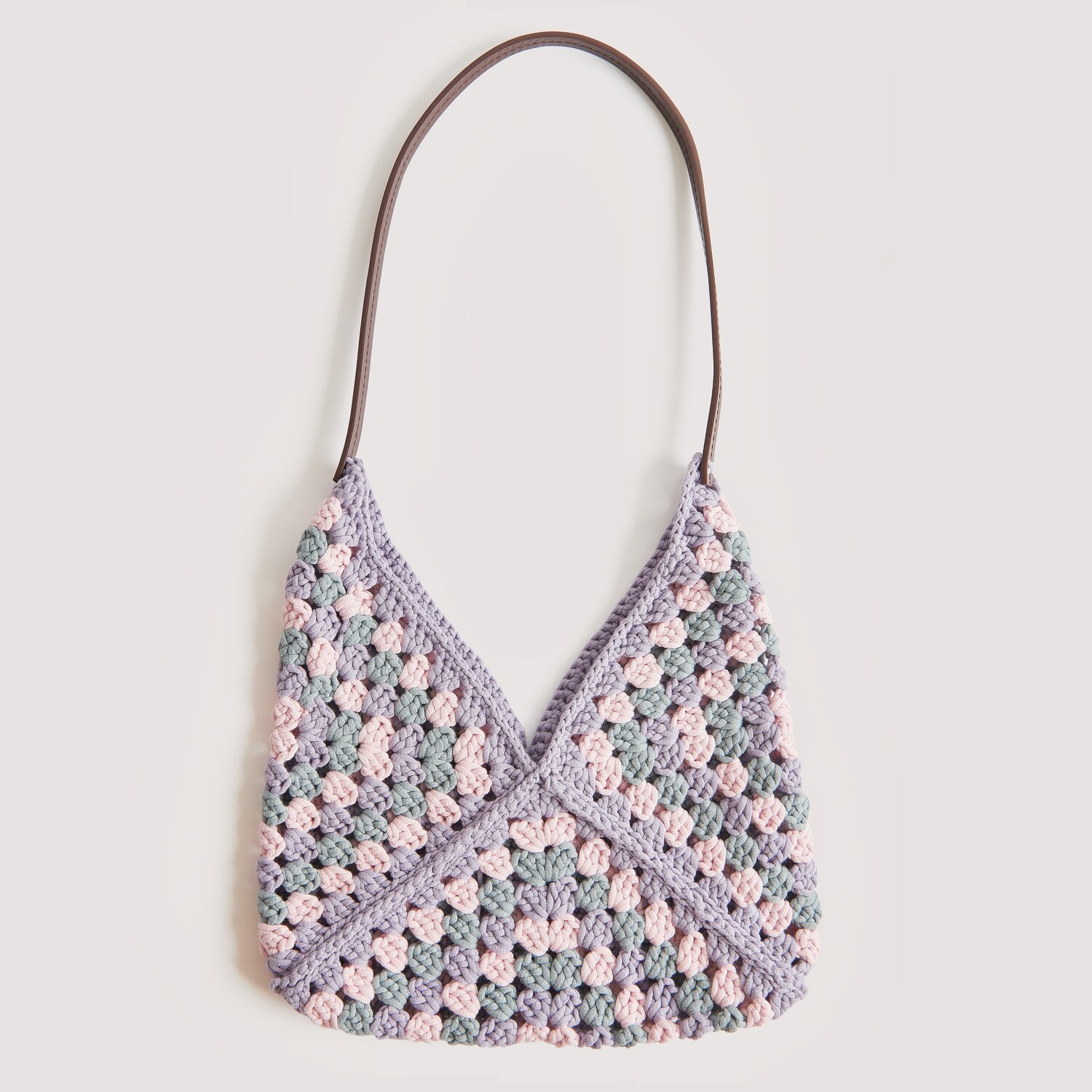Die Neue Masche No. 12 Frühjahr-Sommer von idee. Creativmarkt Die Neue Masche No. 12 Frühjahr-Sommer: Handtasche im Granny-Square-Design aus Lavendel- und Grautönen mit braunem Henkel.