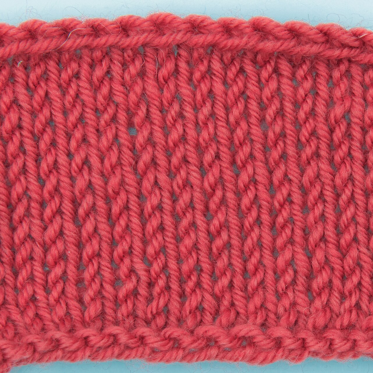 Essentials Merino dk zeigt ein glatt rechts gestricktes Probestück von Rico Design in kräftigem Karminrot, gleichmäßige Maschenstruktur, Garnstärke 50g 110m
