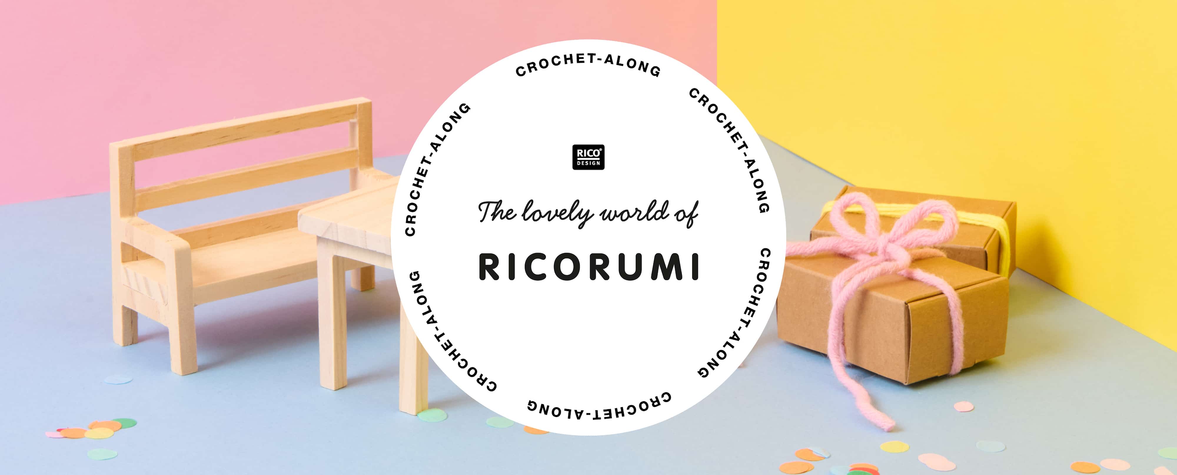 Eine Minaturwelt mit Miniatur-Möbeln und Geschenken ist vor bunten Wänden aufgestellt. Konfetti liegt auf dem Boden verstreut. Davor ein Logo von Ricorumi.