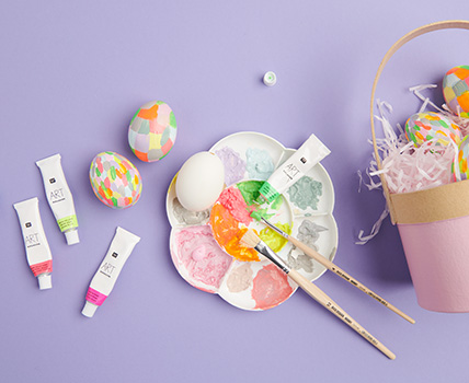 Weiße Eier werden mit Acrylfarben bunt bemalt, Farbpalette und Osterkörbchen sind zu sehen