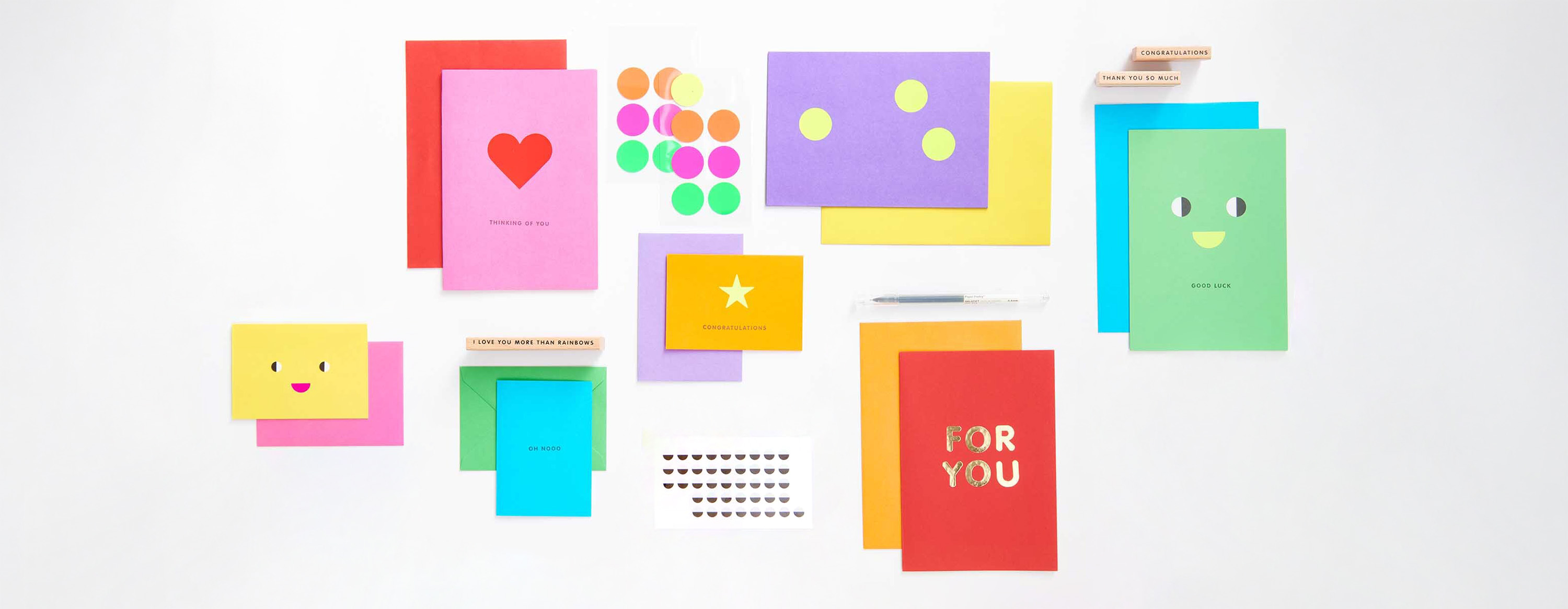 Bunte Karten mit Stickern, Stempeln, Stift und Gesichtern verziert, liegen über und nebeneinander. Flatlay von Produkten.