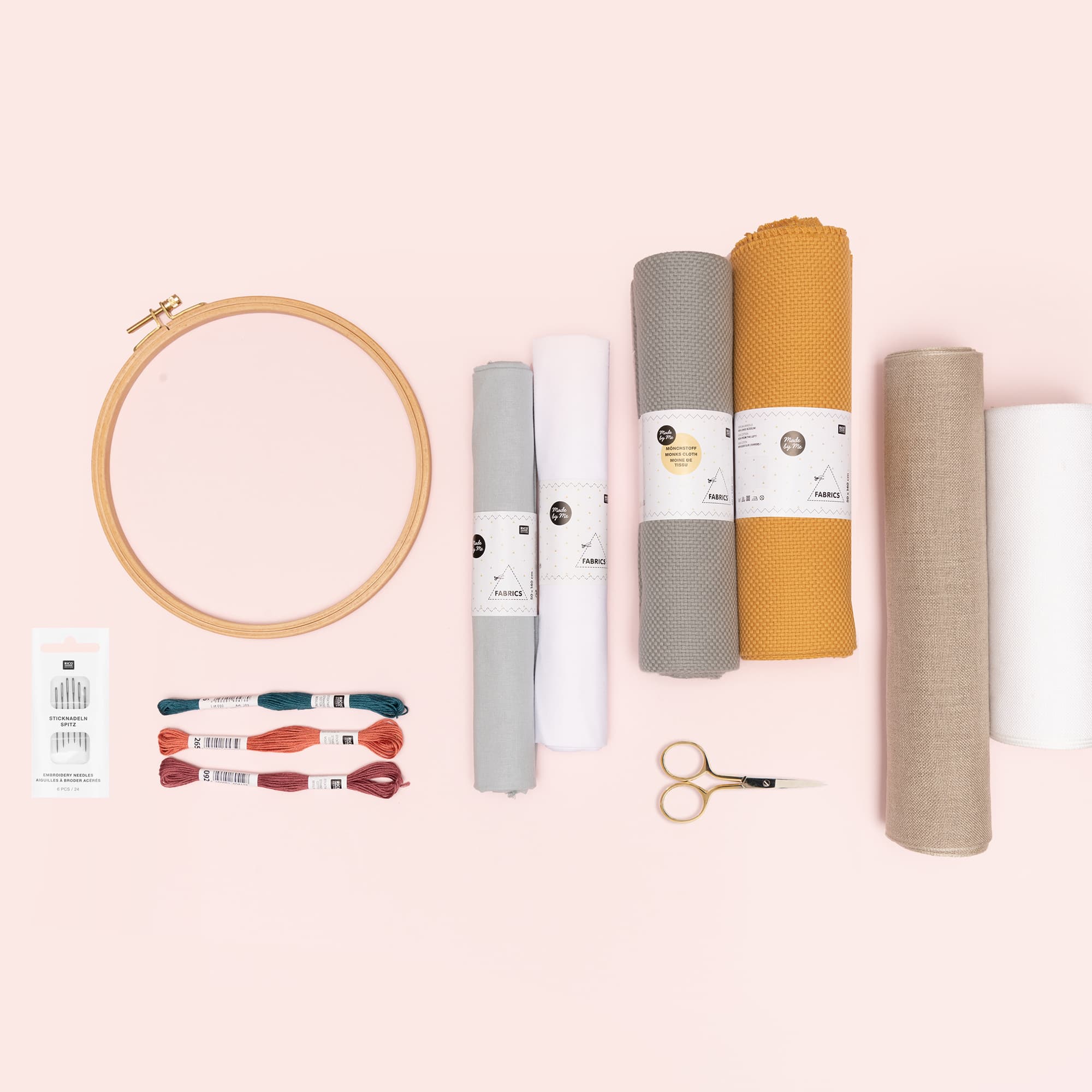 Stickring, Stickgarn, Stoff und Stickzubehör liegen auf rosa Untergrund