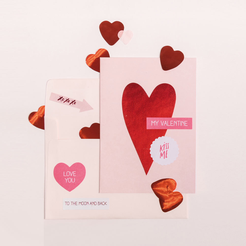 Rosa Karten und Umschlag mit Herz und Sticker verziert. Flatlay von Produkten.