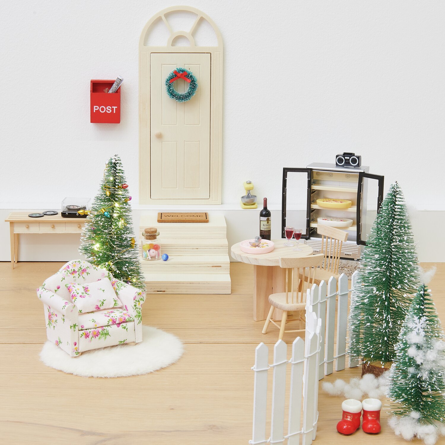 Miniatur Sessel in floralem Design vor weihnachtlicher Kulisse mit Tannenbäumen und Dekoration.
