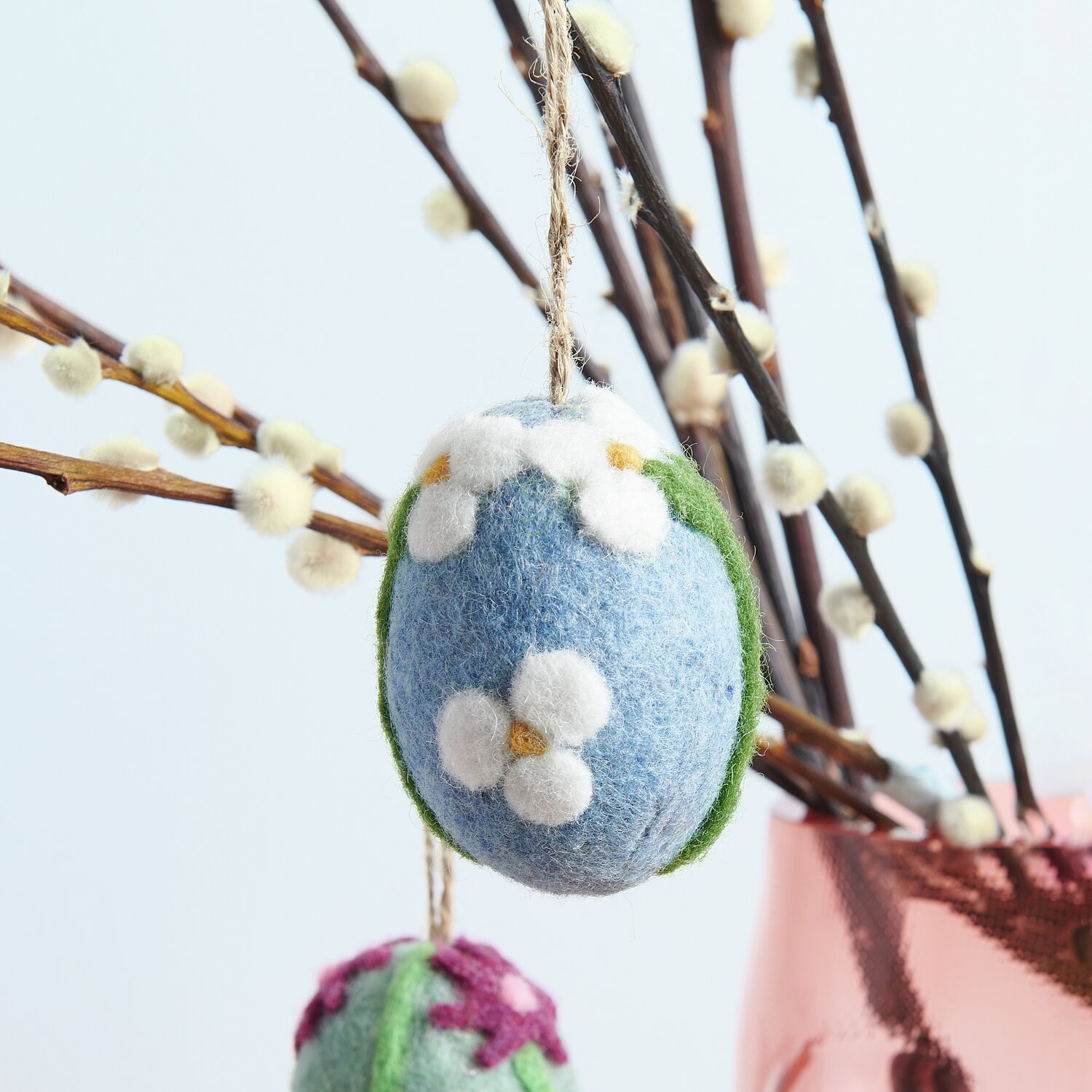 Aufhänger Filz-Ei Apfelblüte: Blaues Filz-Ei mit weißen Blüten, dekorativ an Zweigen hängend. Größe 7,8xØ5,8cm.