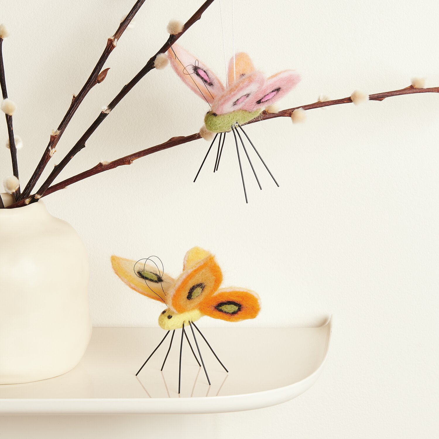 Aufhänger Filz-Schmetterling: Zwei bunte Filz-Schmetterlinge von Rico Design auf Ästen dekoriert.