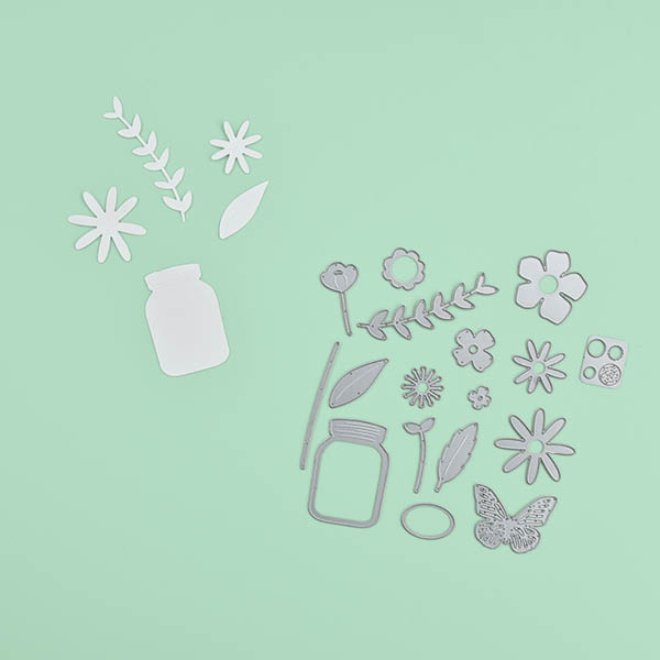 Thinlits in unterschiedlichen Blumenformen und bereits ausgestanztes Papier. Flatlay von Produkten.