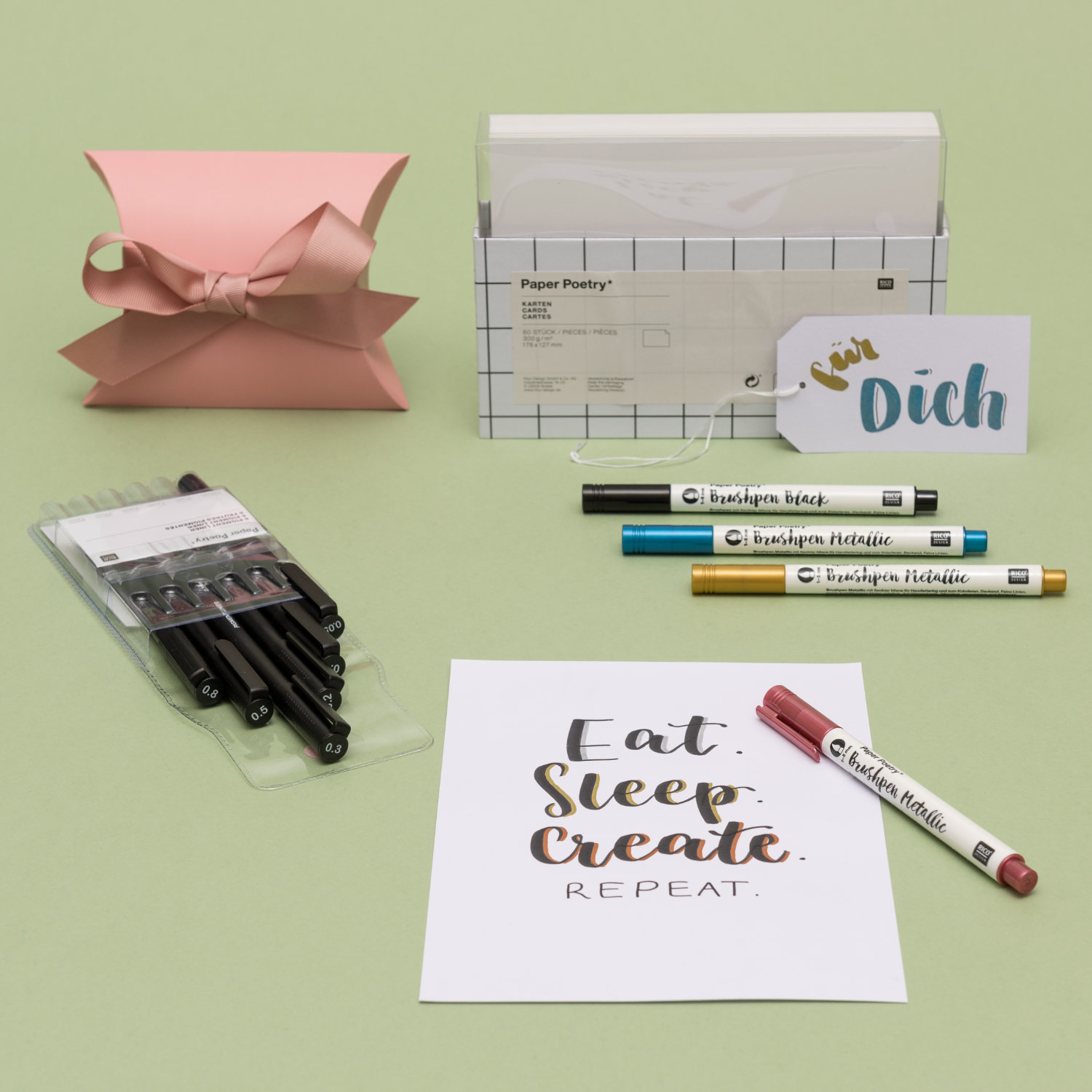 Weiße Karten in der Verpackung, eine Geschenkschachtel, eine beschriftete Karte und Geschenkanhänger mit Brushpens und verpackten Pigment Linern.