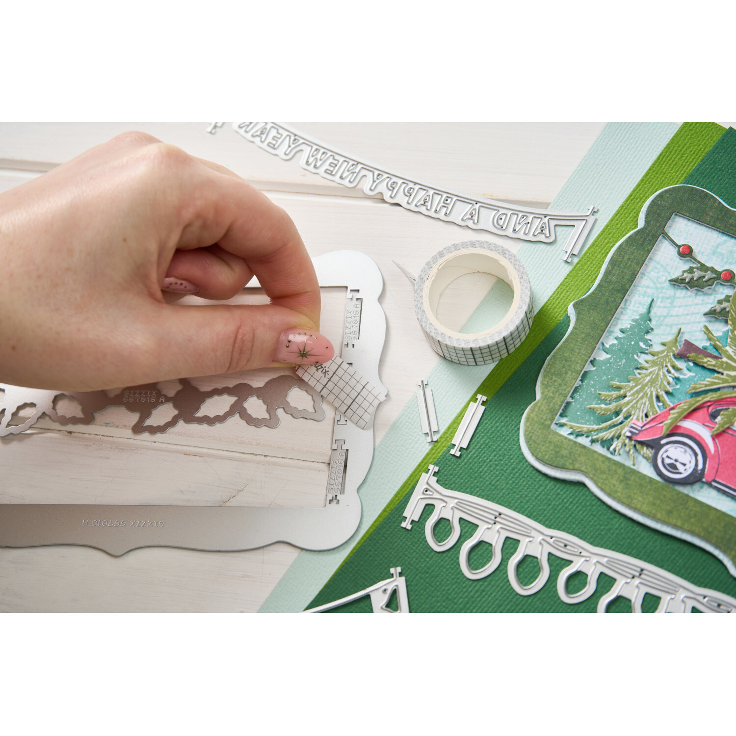 Thinlits Die Set Snap and Swap Merry Christmas: Hand arrangiert Stanzteile auf grünem Papier, Sizzix, 15-teilig, mit Klebeband und Weihnachtsmotiv.