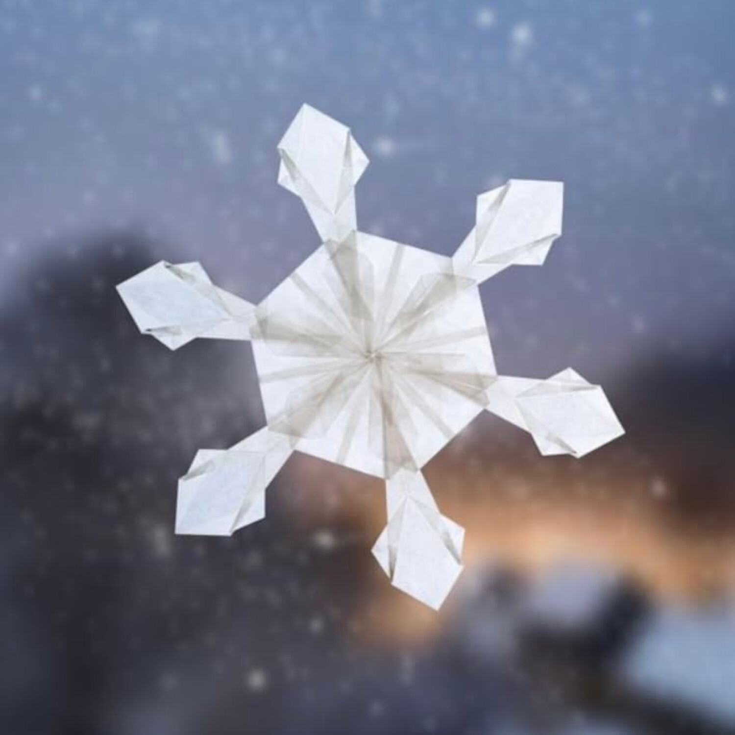 Schneekristalle aus Transparentpapier: Filigraner weißer Kristall vor winterlicher Kulisse. Ideal für kreative Dekorationen.