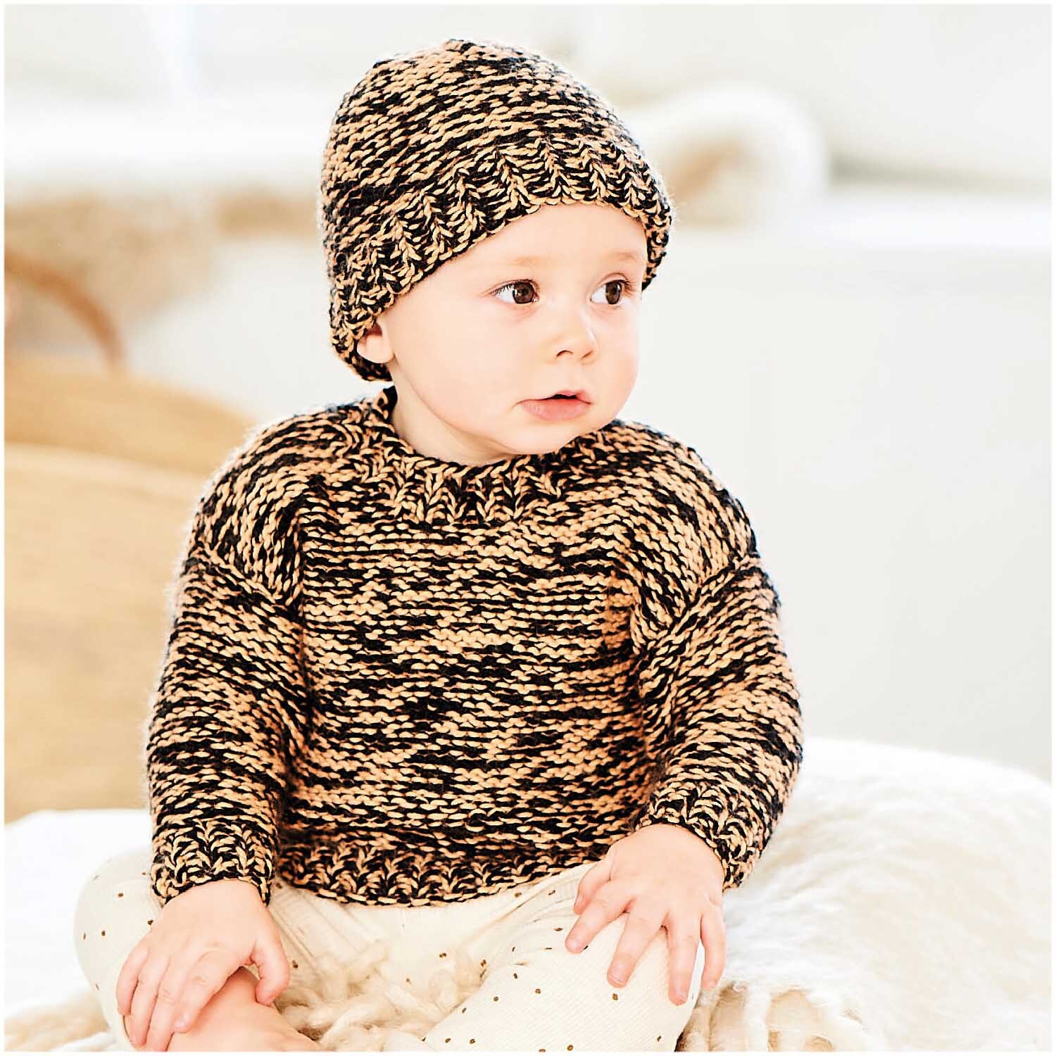 Rico Baby Dream dk uni - A Luxury Touch: Baby in gestricktem Outfit aus schwarzem Garn von Rico Design, sitzt auf einer Decke.