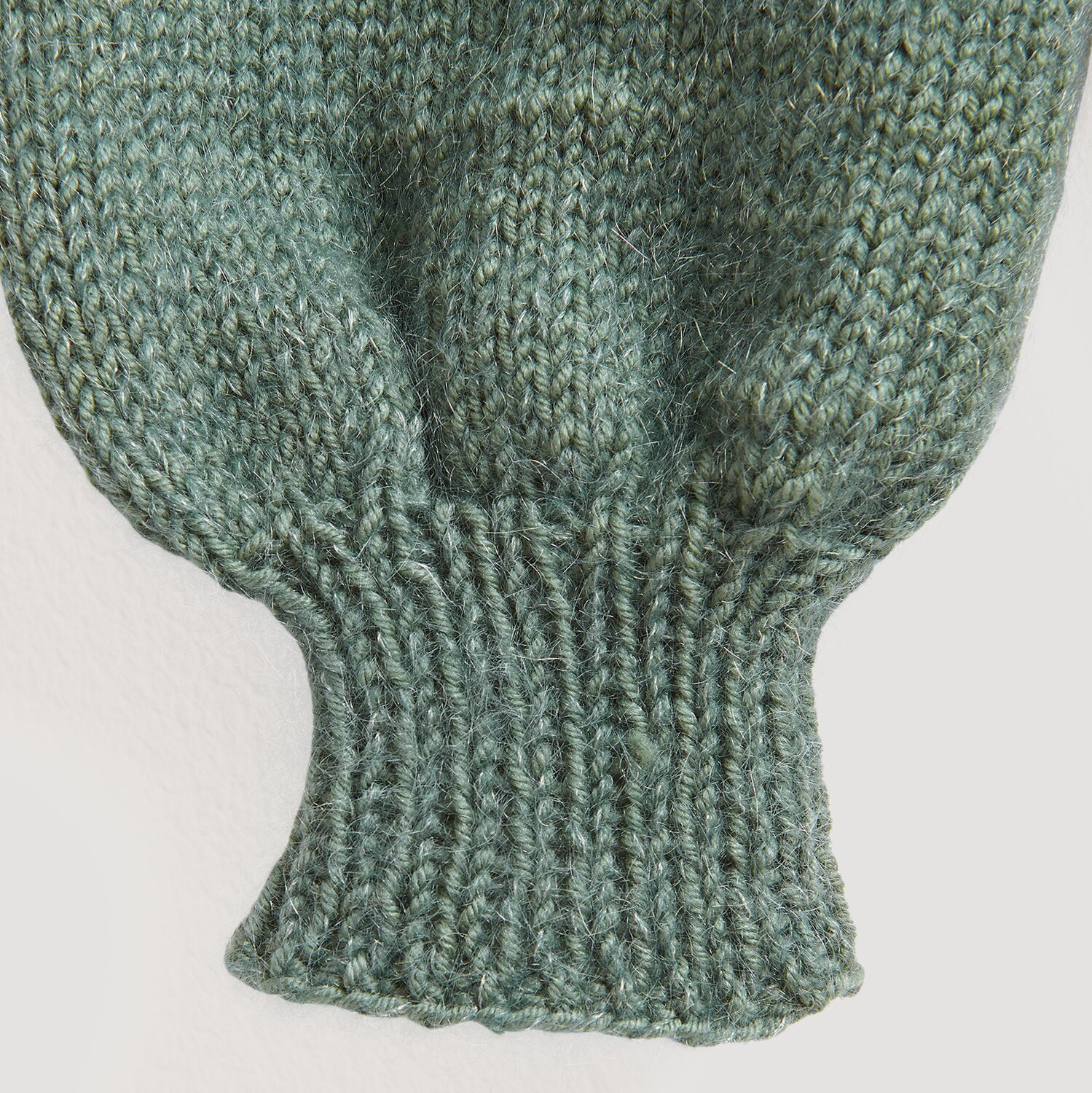 Die Neue Masche No. 13 Herbst von idee. Creativmarkt Essentials Merino dk: Nahaufnahme eines gestrickten Ärmels in Efeu-Grün, weiche Textur.