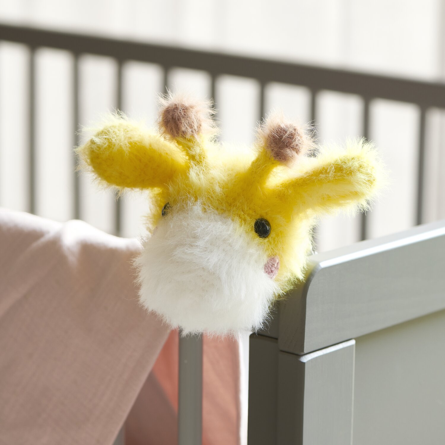 Ricorumi Furry Furry 25g 175m Farbe Weiß von Rico Design Ricorumi Furry Animals: Gelbe und weiße gestrickte Giraffe mit schwarzen Sicherheitsaugen am Kinderbett.