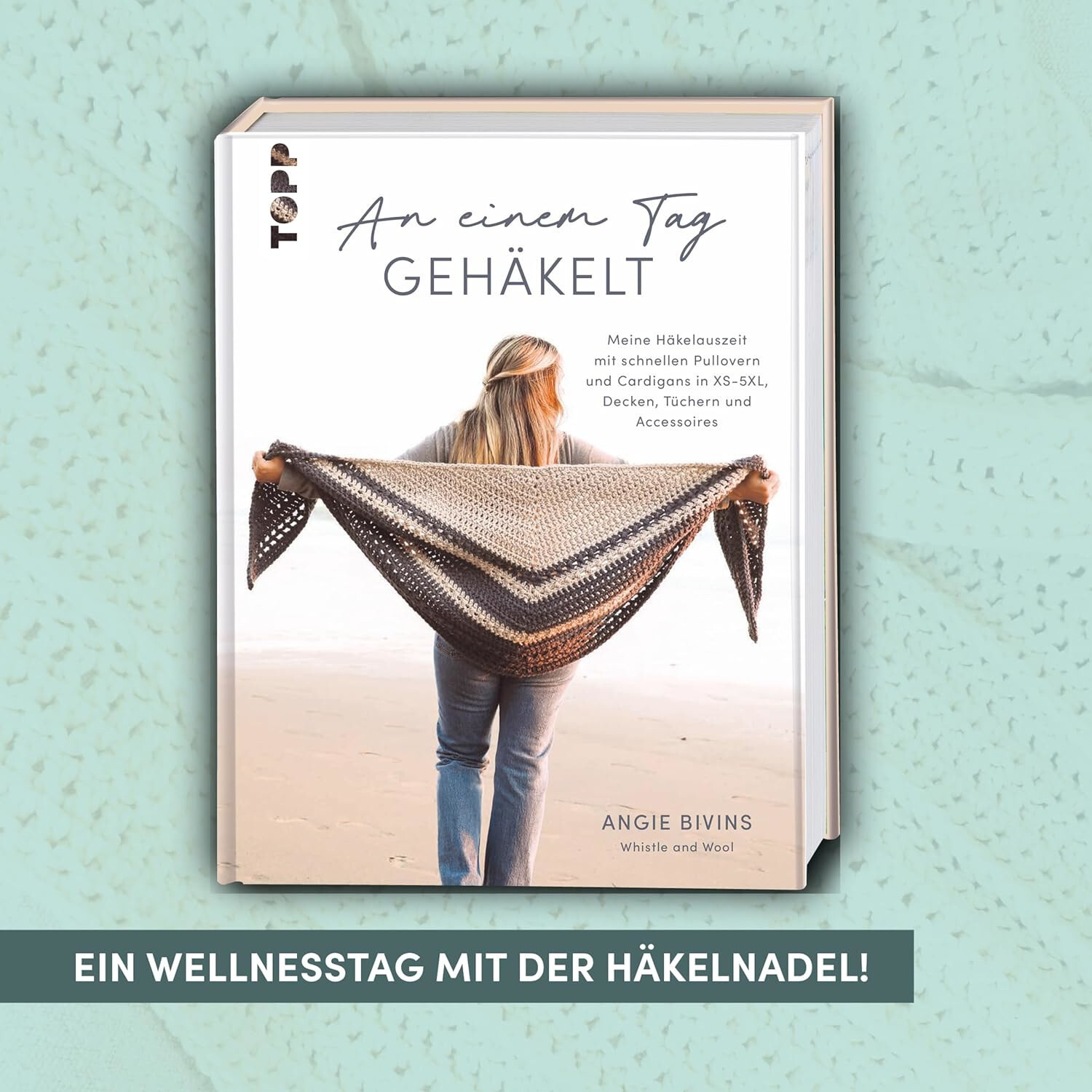 An einem Tag gehäkelt: Buchcover mit Frau am Strand, die ein gehäkeltes Tuch präsentiert.
