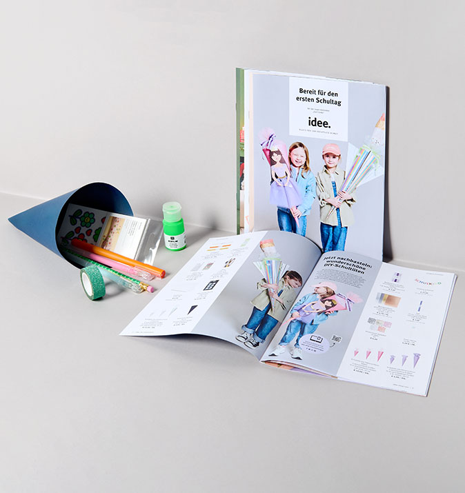 idee. Prospekt liegt in grauer Ecke mit Schultüte daneben