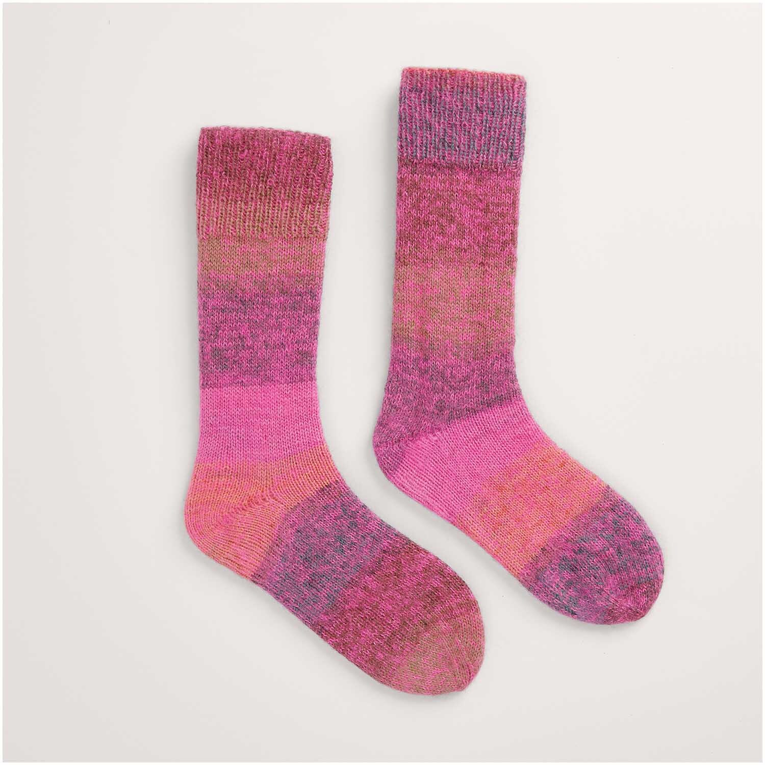 Zwei gestrickte Socken in Rosa- und Violetttönen, präsentiert als Legeware. Teil des Stricksets "Socken Modell 45" aus der Kollektion "Made by Me Nr. 17". Ideal für DIY-Projekte.