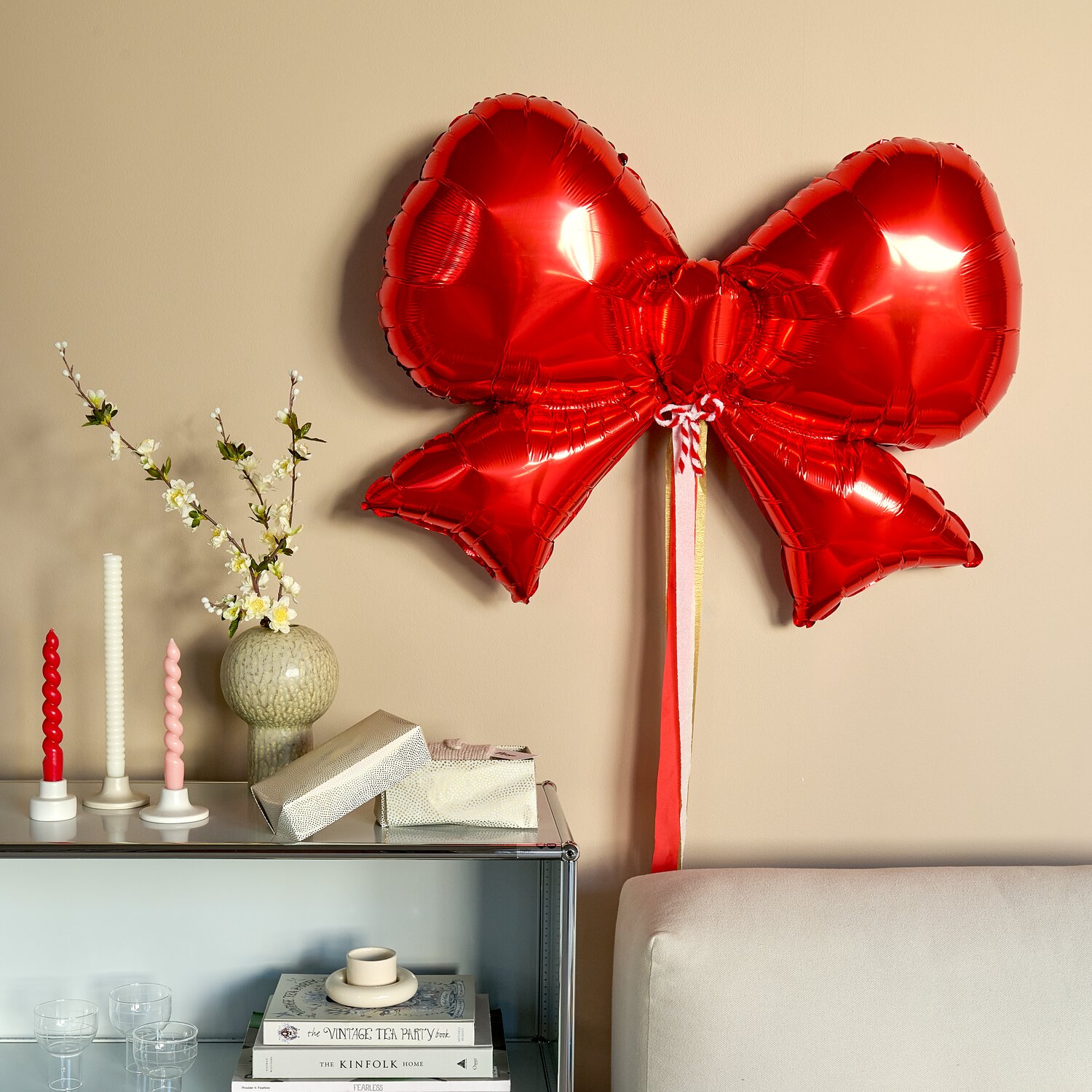 Folienballon Advent Schleife Rot, Rico Design, festliche Schleifen-Deko über Sideboard mit Kerzen, Büchern und Geschenken, ideal als auffälliger Weihnachtsschmuck