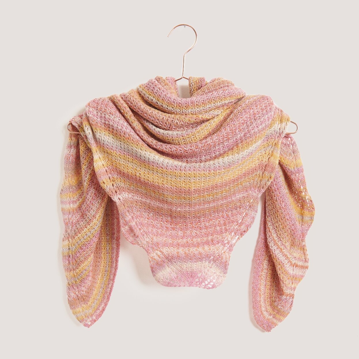 Strickset Dreieckstuch Modell 06 aus Tücher Special in Pastel, präsentiert auf einem Kleiderbügel. Ideal für modische Strickprojekte.