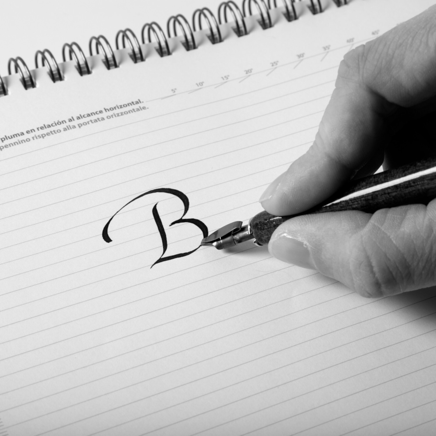 Kalligrafiefedern Set Bandzug, 3-teilig: Hand schreibt Buchstaben auf liniertes Papier mit schwarzer Tinte.