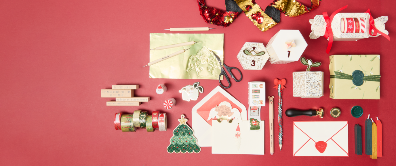 Kreativmaterialien für weihnachtliche Karten, Geschenke und Dekorationen auf rotem Hintergrund.
