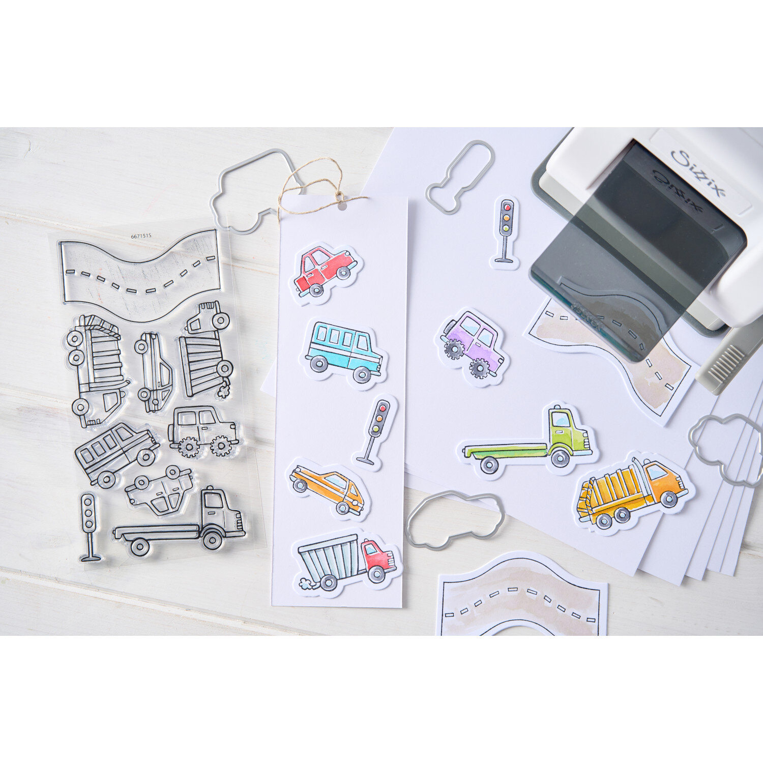 Sizzix Clear Stamps/Framelits Cars and Trucks Set 9 Stk zeigt bunte Stempel- und Stanzmotive mit Autos, Lastwagen, Straßen und Ampeln auf weißem Basteltisch