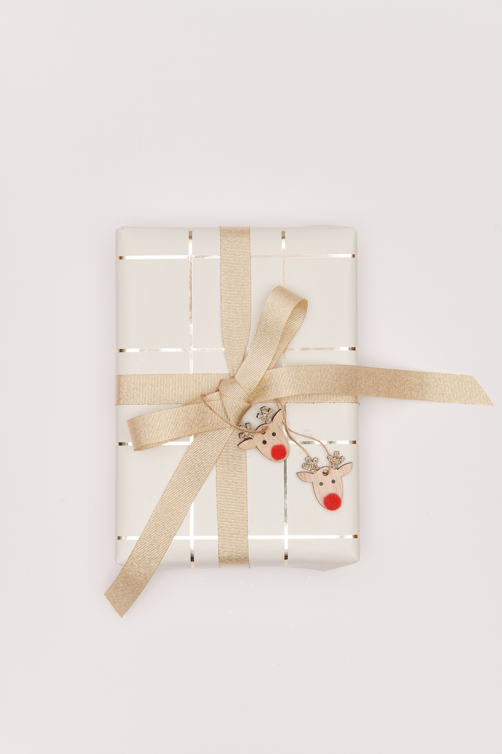 Holzhänger Rentier mit Glitter, dekoriert auf einem Geschenk mit beigem Band, von Rico Design.