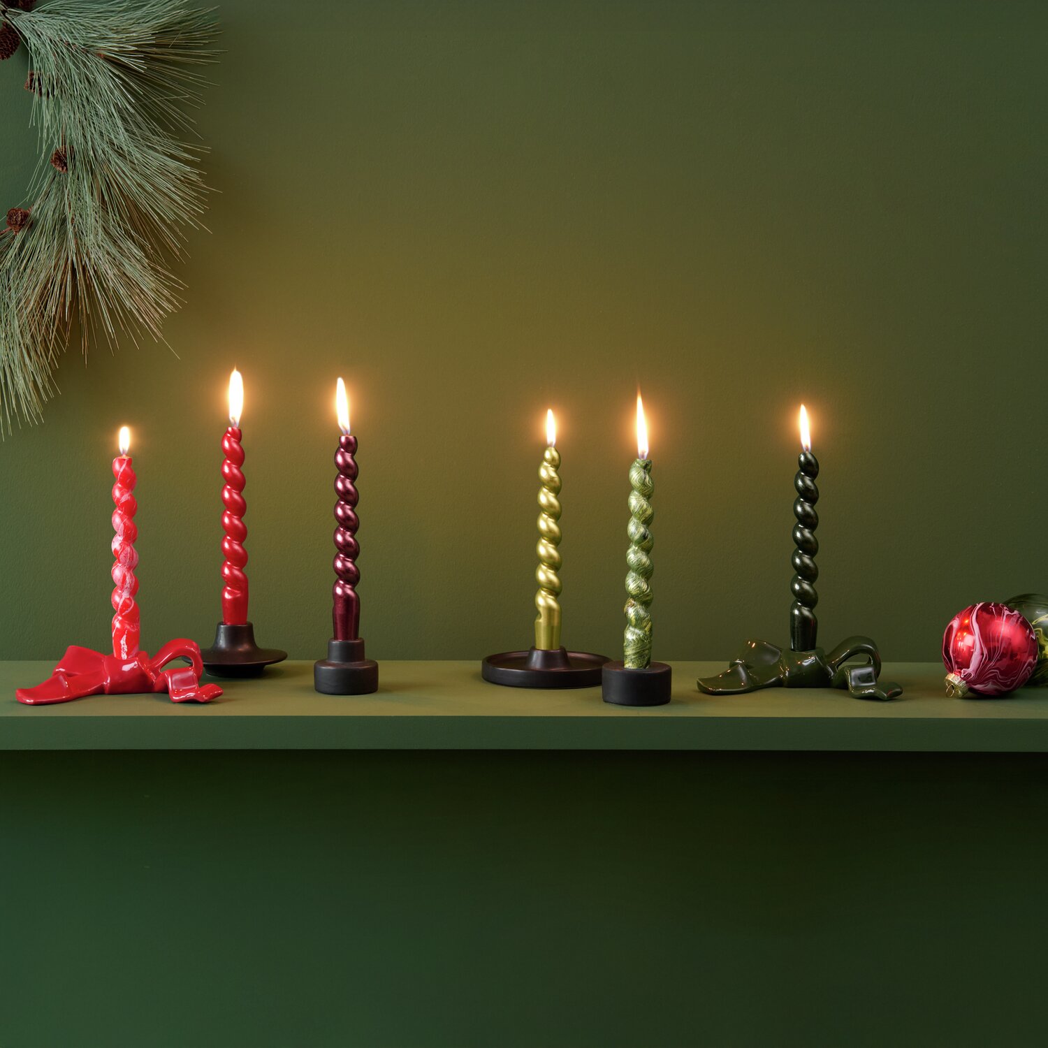 Spiralkerze marmoriert 2,4x18,5cm leuchtet auf grünem Regal mit Kerzenhaltern und Weihnachtsdeko.