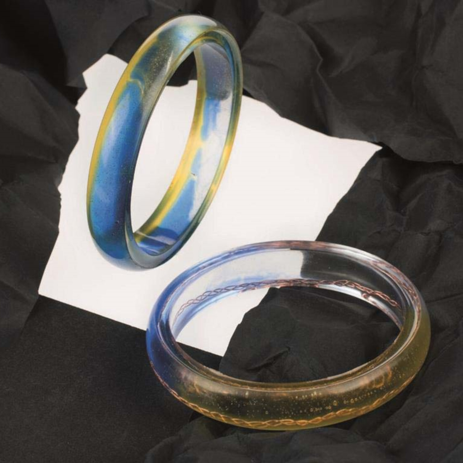 Crystal-Gießharz: Zwei bunte Armbänder aus transparentem Harz auf schwarzem Hintergrund. Ideal für DIY-Schmuckprojekte.