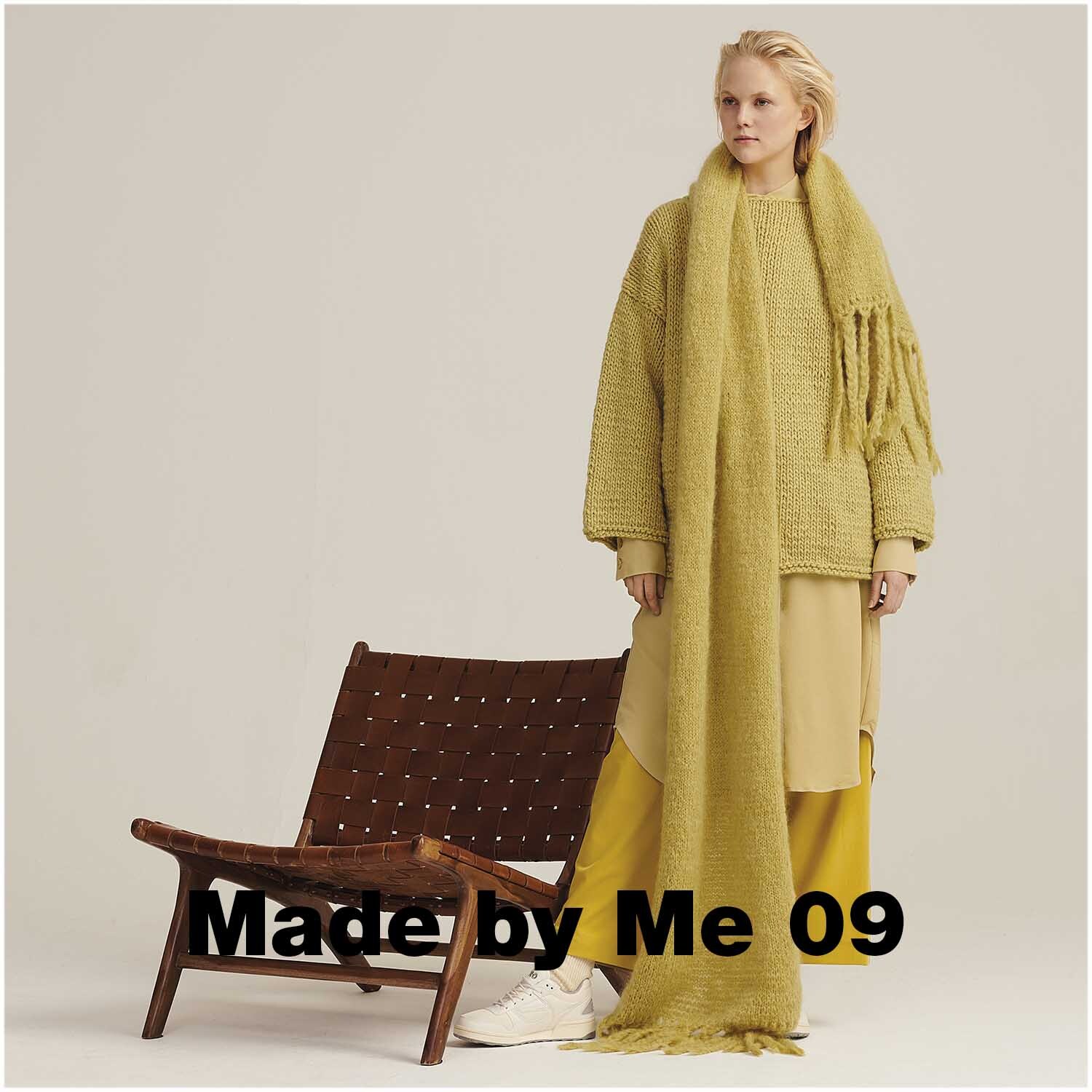 Fashion Mohair Merino Chunky: Frau in senffarbenem Strickoutfit von Rico Design neben einem Stuhl.