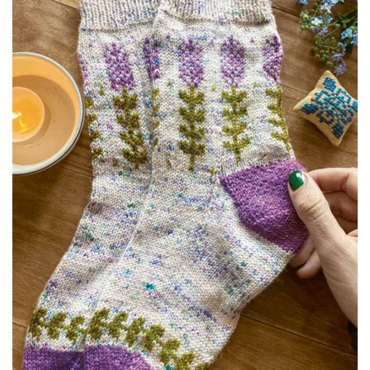 Einzigartige Motivsocken stricken: Handgestrickte Socken mit lila und grünen Mustern auf Holztisch.