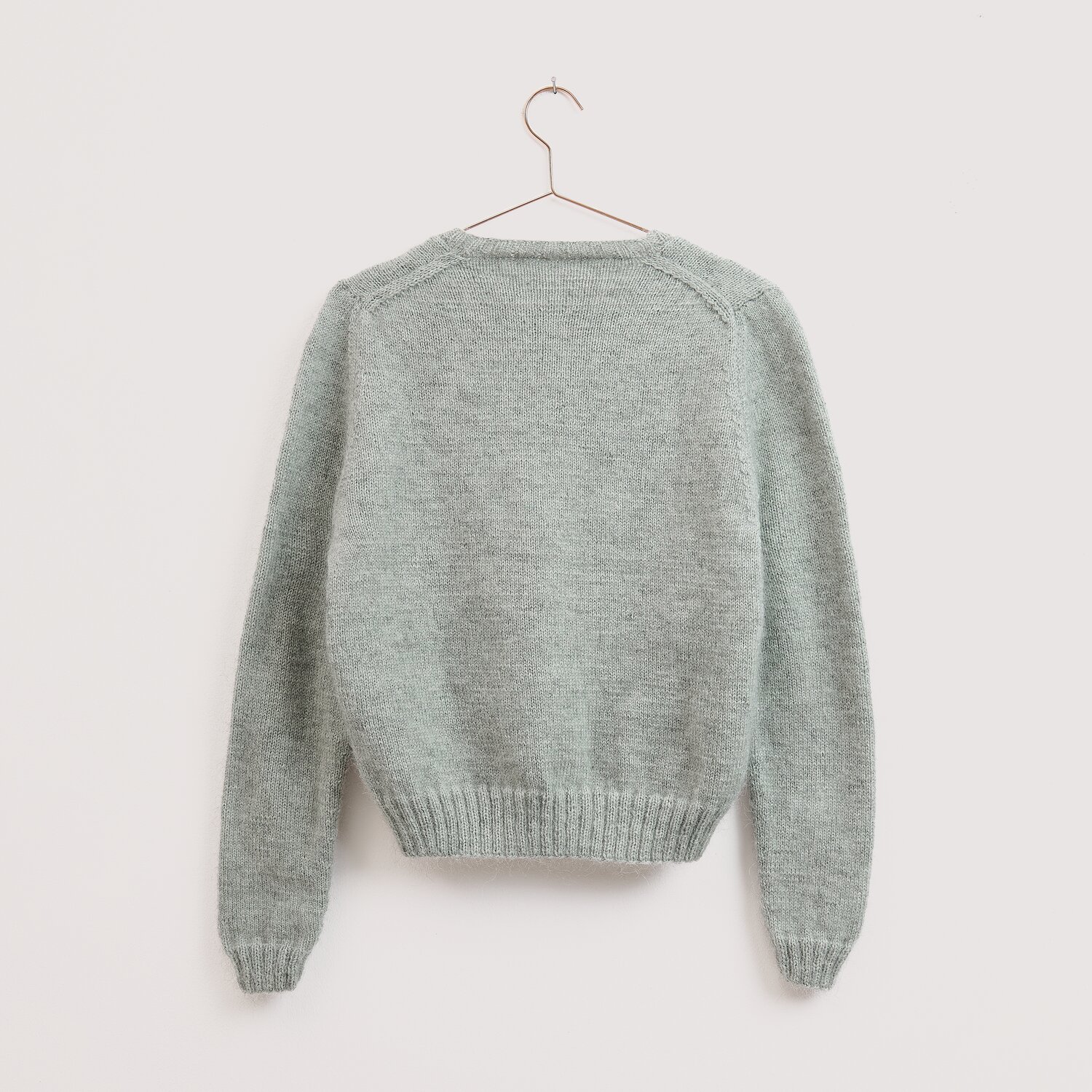 Die Neue Masche No. 16 Herbst Pullover von Wolle Rödel, locker gestrickt, langärmelig, gerader Schnitt mit Rippbündchen, aufgehängt vor neutralem Hintergrund