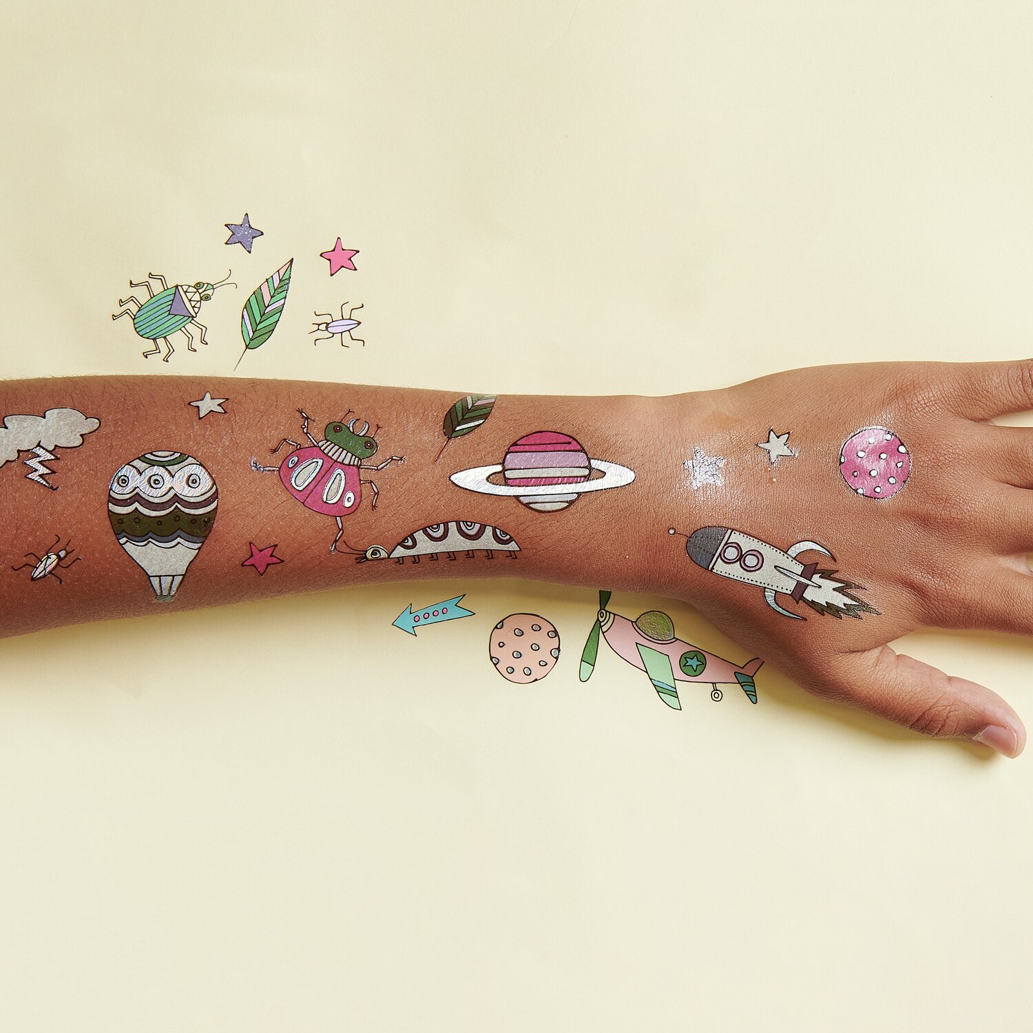 Tattoos Monsterparty: 21-teiliges Set mit bunten Weltraum- und Monster-Motiven auf einer Hand.
