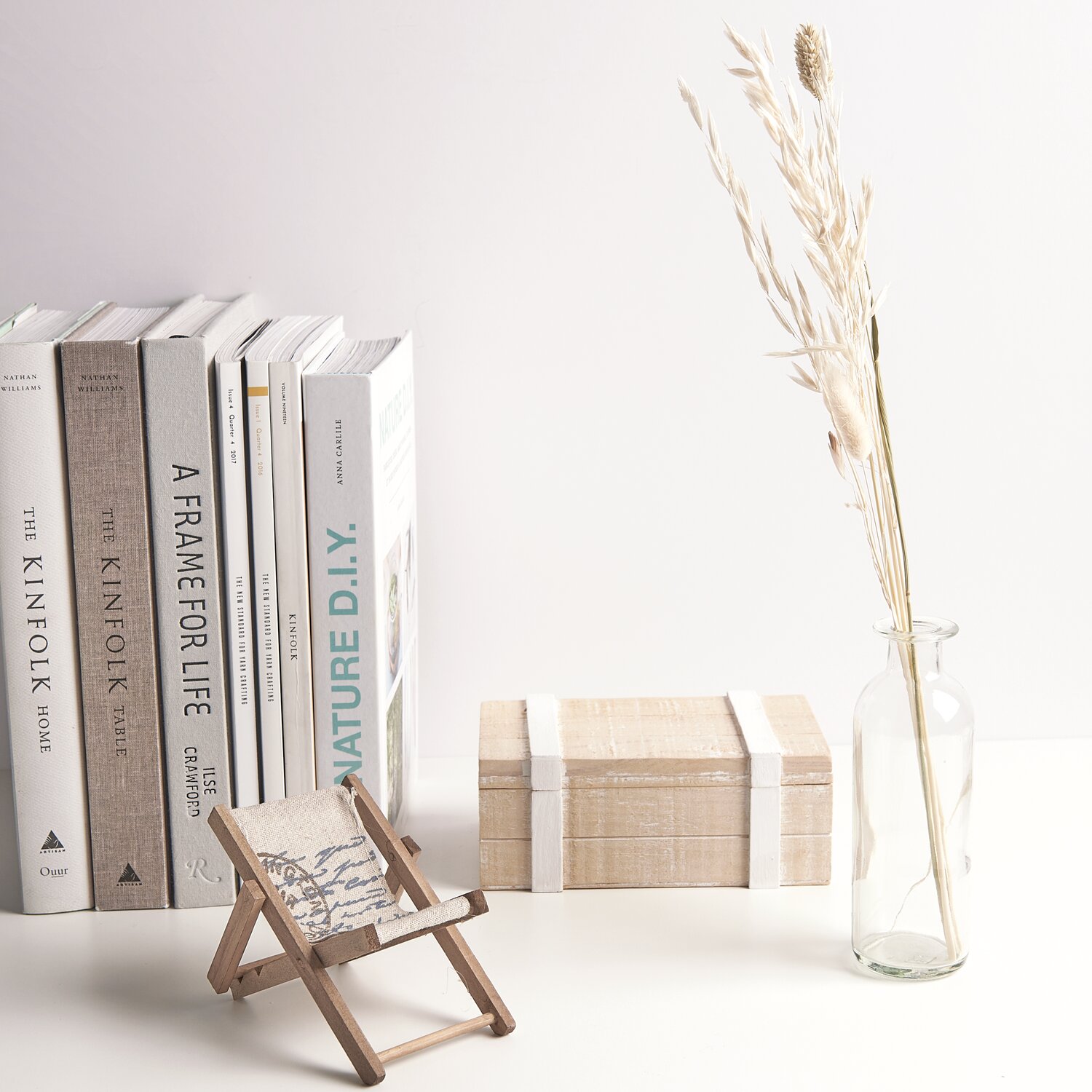 Glasvase klar 16x5cm mit Trockenblumen neben Büchern und Miniaturstuhl auf weißem Tisch.