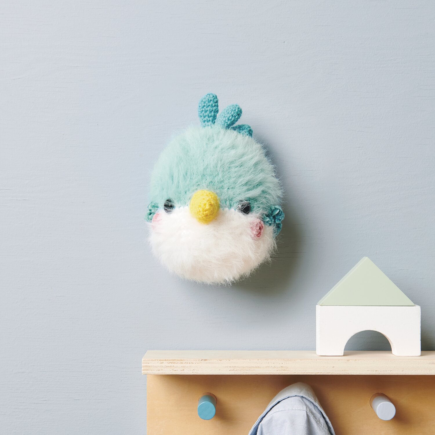 Ricorumi Furry Furry 25g 175m Farbe Weiß von Rico Design Ricorumi Furry Animals: Flauschiger türkis-weißer Vogel mit gelbem Schnabel an blauer Wand.