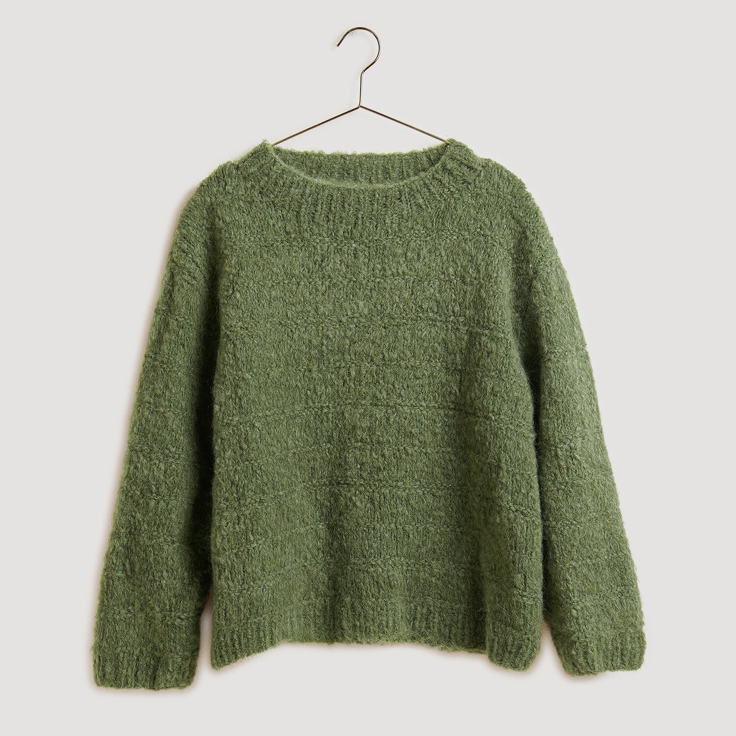 Die Neue Masche No. 13 Herbst von idee. Creativmarkt Strickset Pullover Modell 21 in Oliv aus Fashion Alpaca Superfine Heavens Uni, präsentiert auf einem Kleiderbügel. Ideal für die Herbstsaison.