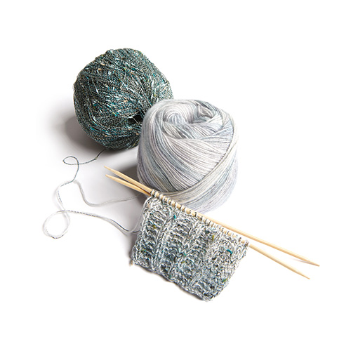 Ein buntes garn und ein Beilaufgarn mit einem Strickstück und Stricknadeln.