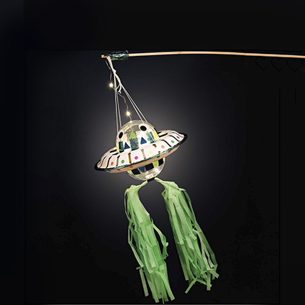 Laterne in UFO-Design mit grünen Akzenten. Fotosetting schwarze Wand.