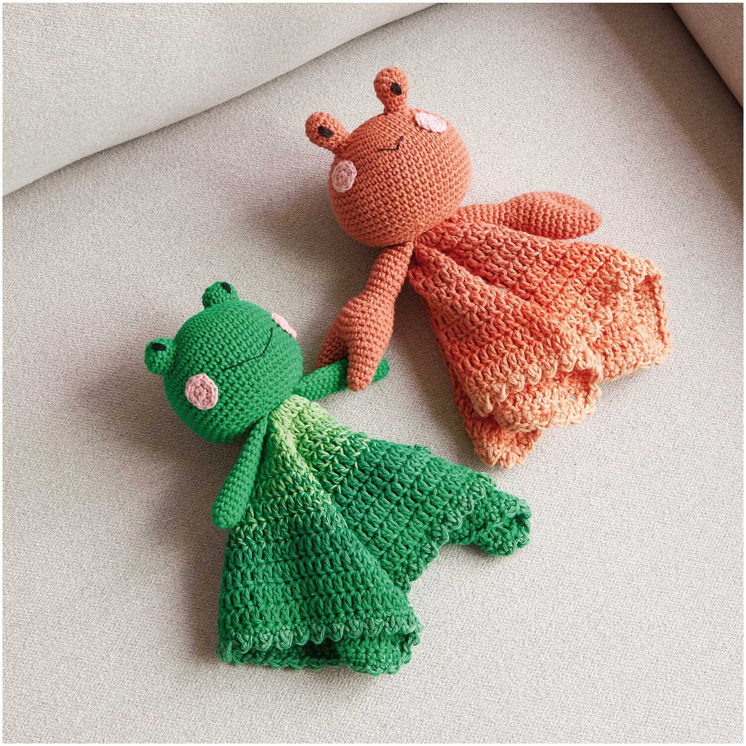 Ricorumi Spin Spin dk: Zwei gehäkelte Kuscheltiere, eines in Orange, das andere in Grün, auf einem Sofa.