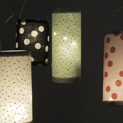 Vier verschiedene gebastelte Laternen aus Stoff mit Punkten und kleinen Zeichen.
