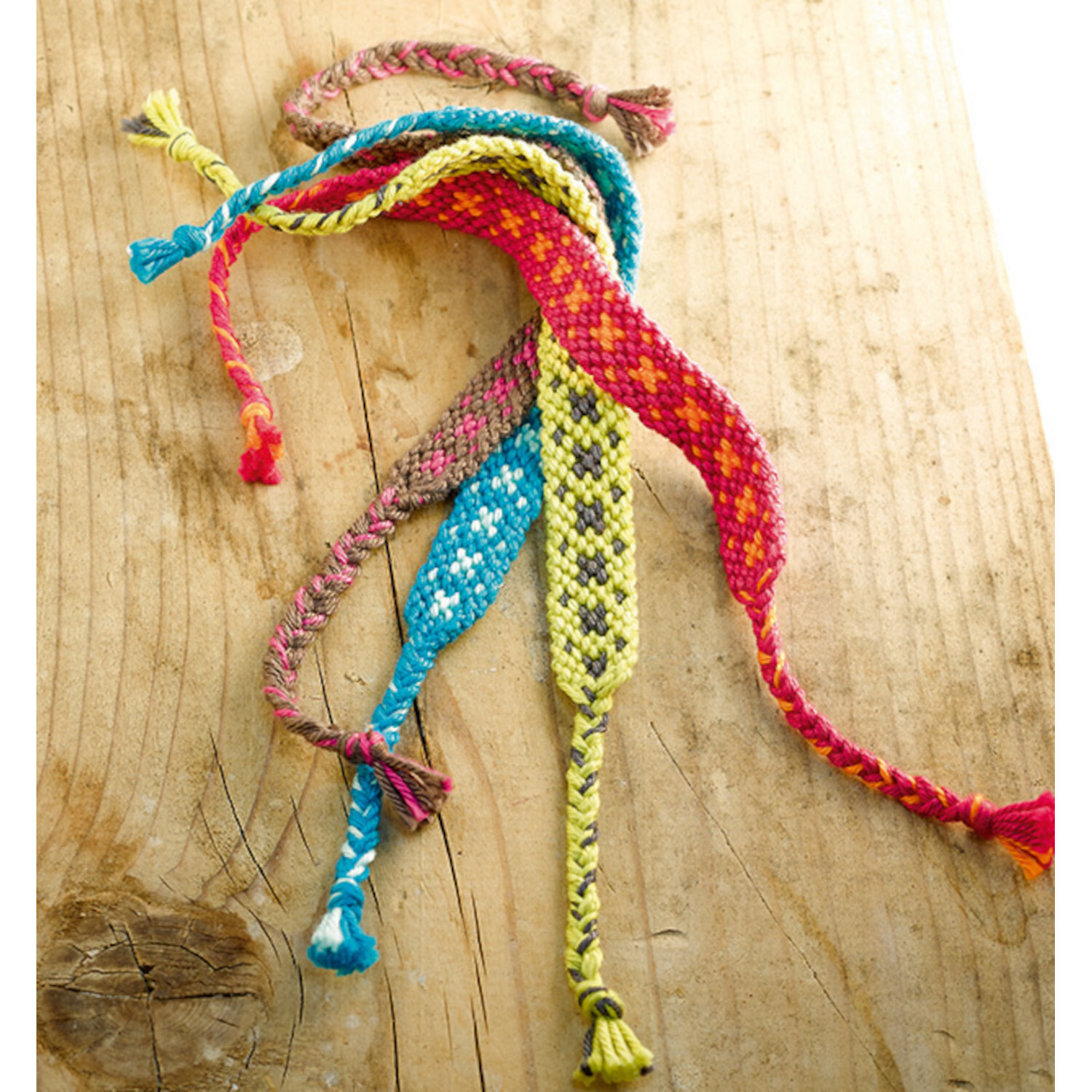 Freundschaftsbänder - Die beliebtesten Muster: Bunte, handgeknüpfte Armbänder auf Holzuntergrund.