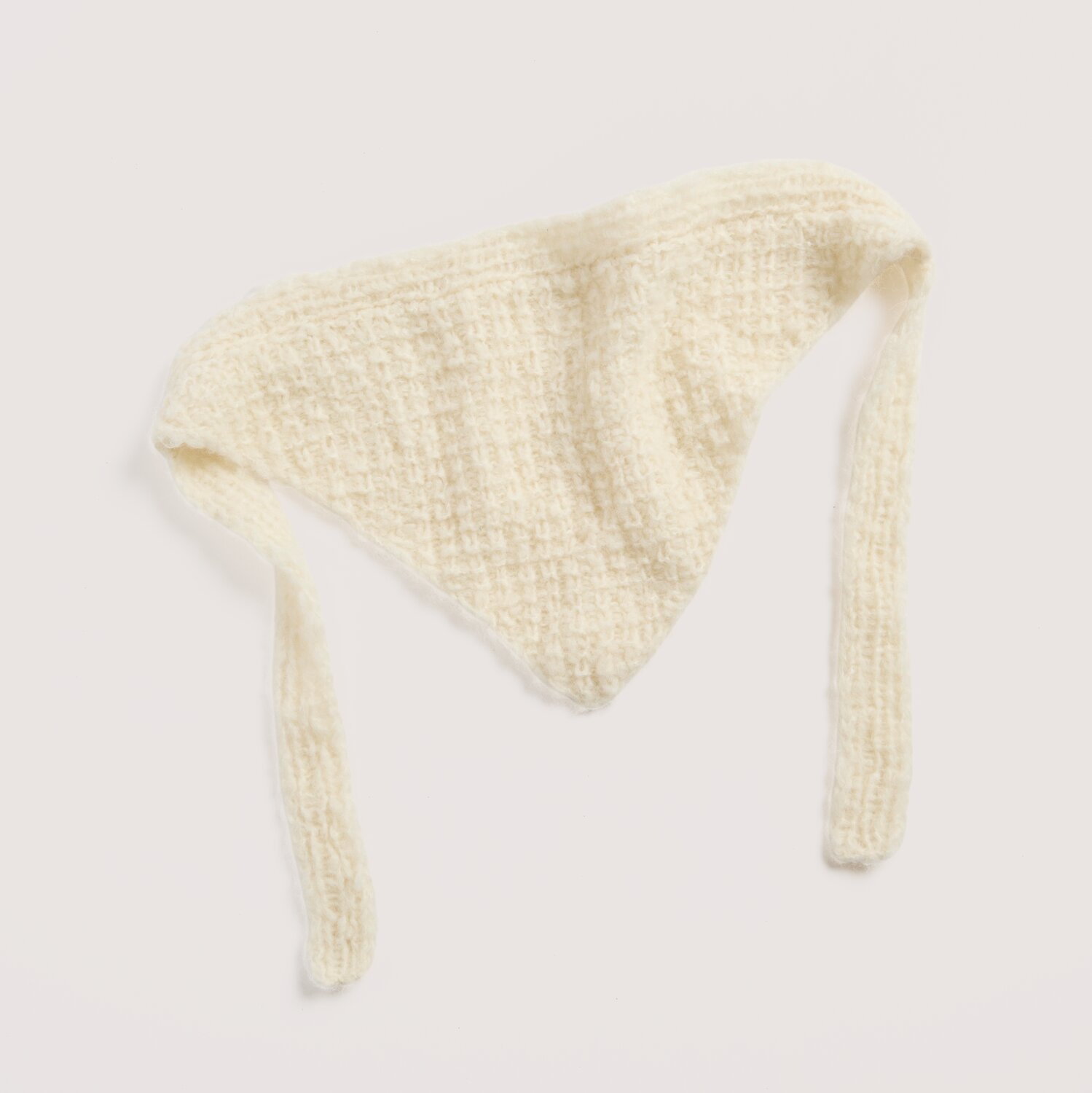 Strickset Dreieckstuch Modell 19 aus Luxury Knits Little Pieces, weiches cremefarbenes Tuch in Dreiecksform mit langer Bindekante, liegend vor neutralem Hintergrund