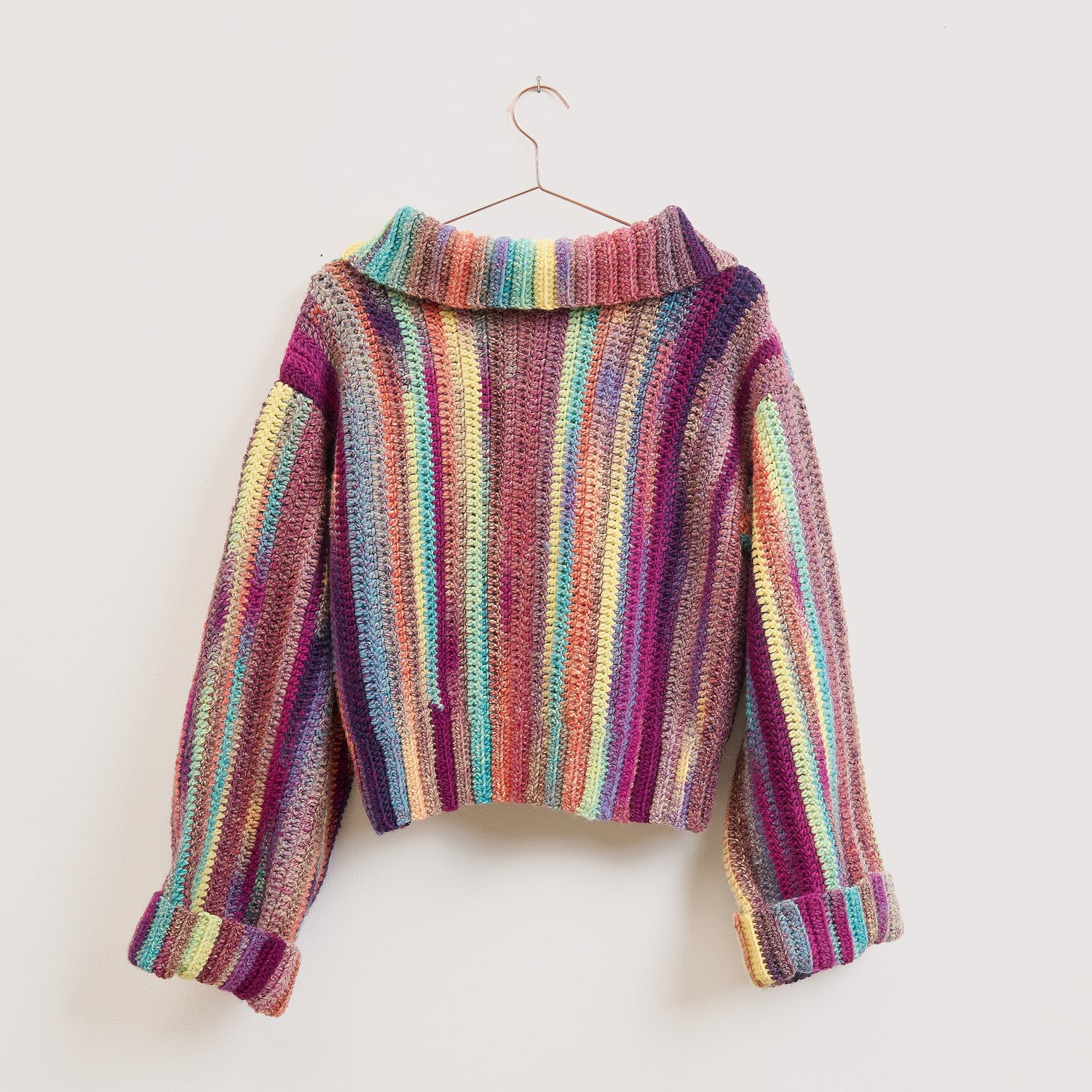 Die Neue Masche No. 16 Herbst, gestrickter Pullover von Wolle Rödel mit bunten Ringelstreifen, langen Ärmeln, breitem Kragen und Aufhänger an neutraler Wand
